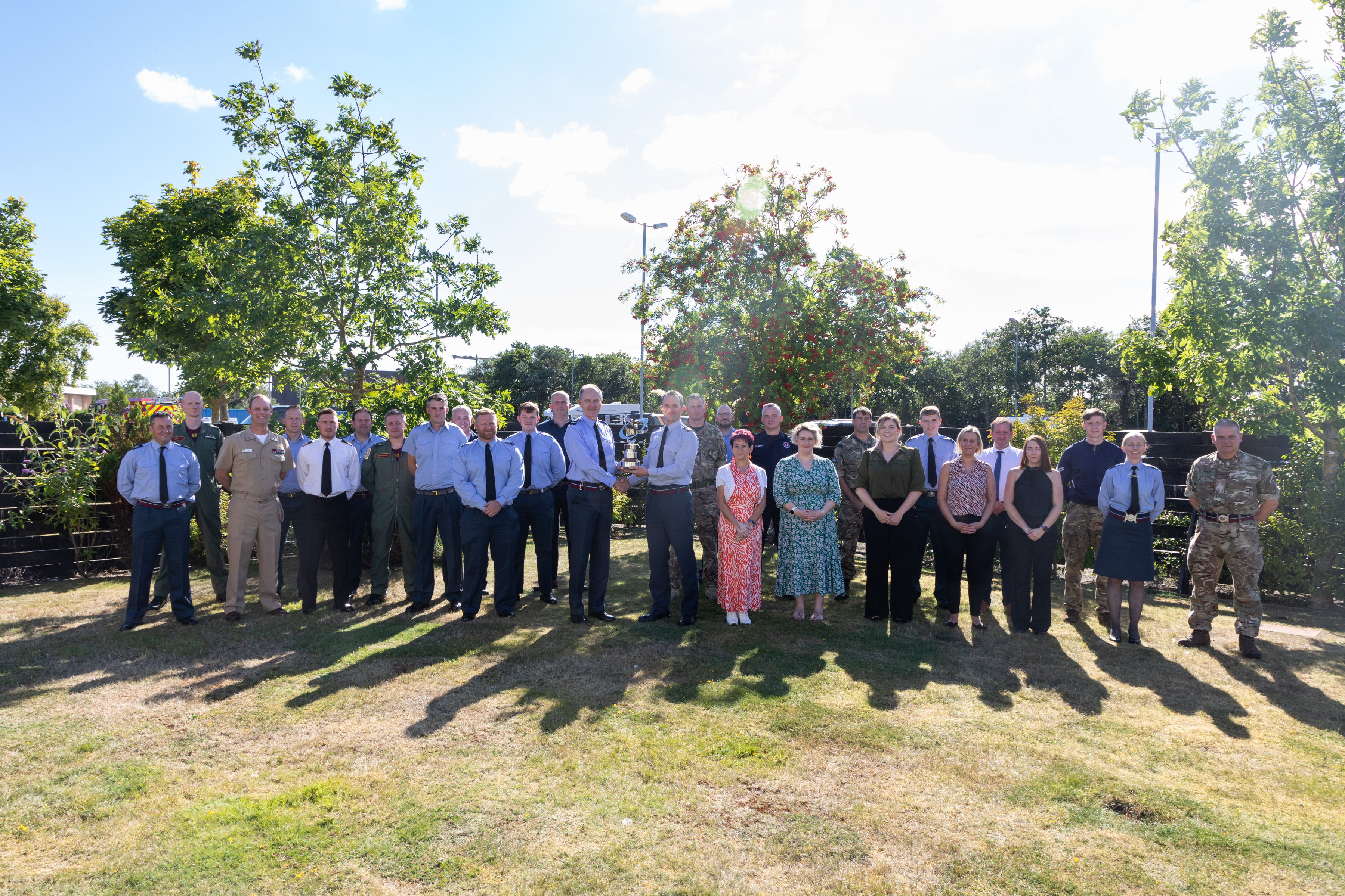 Image shows personnel and civilians outside for group photo.